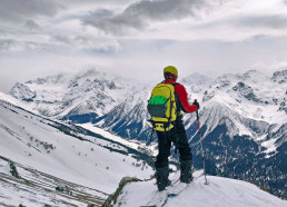 narciarz skitutowy z plecakiem na szczycie góry